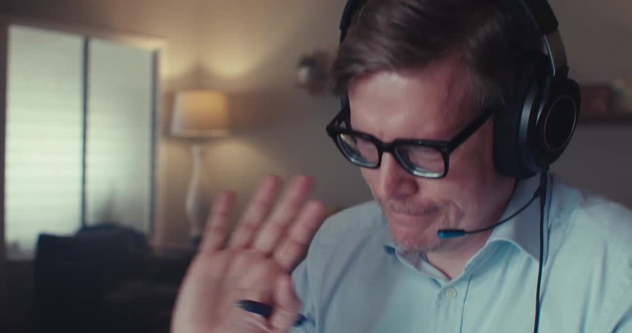 The man talks on a microphone and waves at a laptop