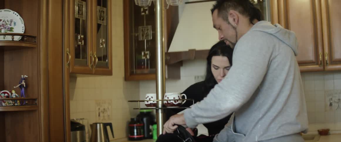 A woman helps a man put items into a sports duffle bag