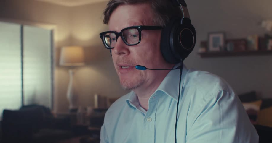 A man is talking into his headset and using a laptop