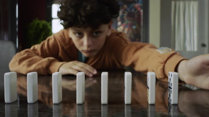 The boy topples the row of dominoes