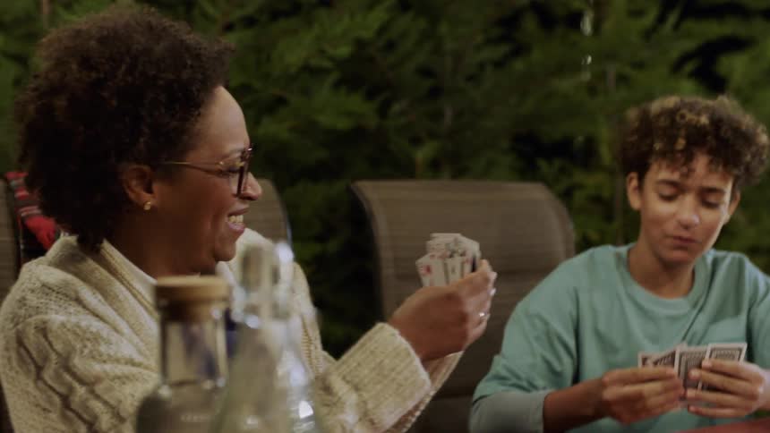 Kids play cards and react joyfully during a lively outdoor family evening