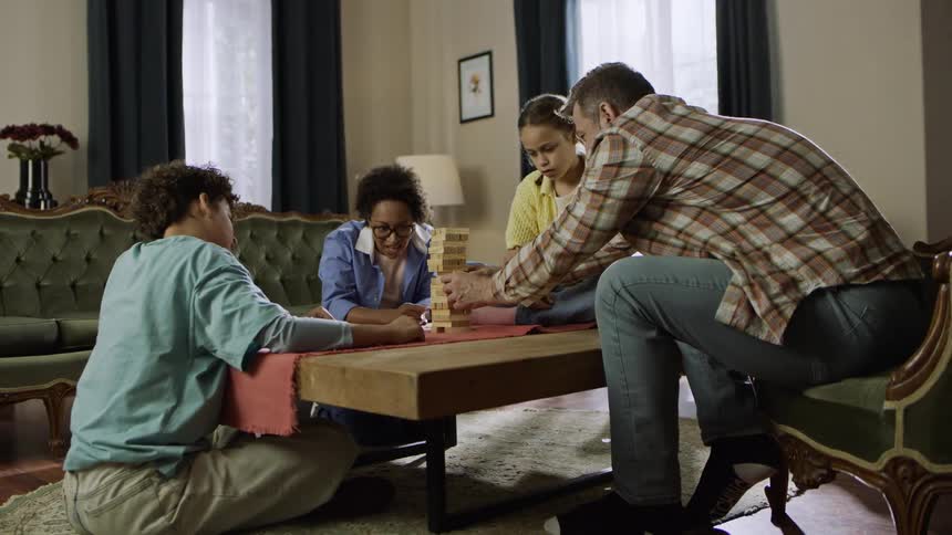 A family of four playing jenga on a wooden table in the living room