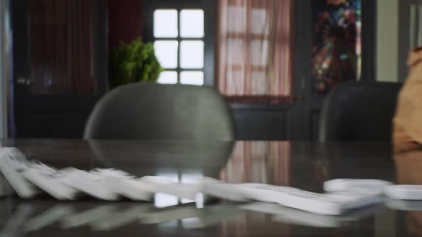 Boy knocking over a stack of dominoes on the table