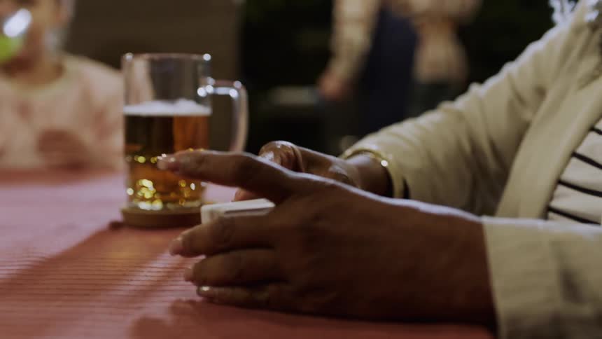 Close up of a black womans hands as she shuffles a deck of cards on a restaurant table at night