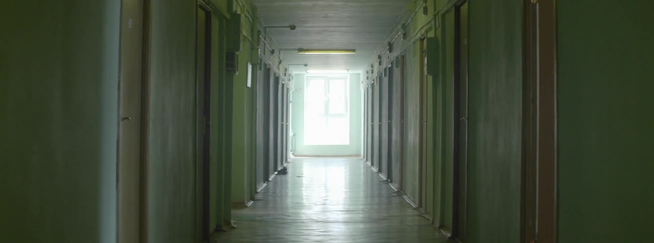 A hallway with a large window at the end with the sun shining through