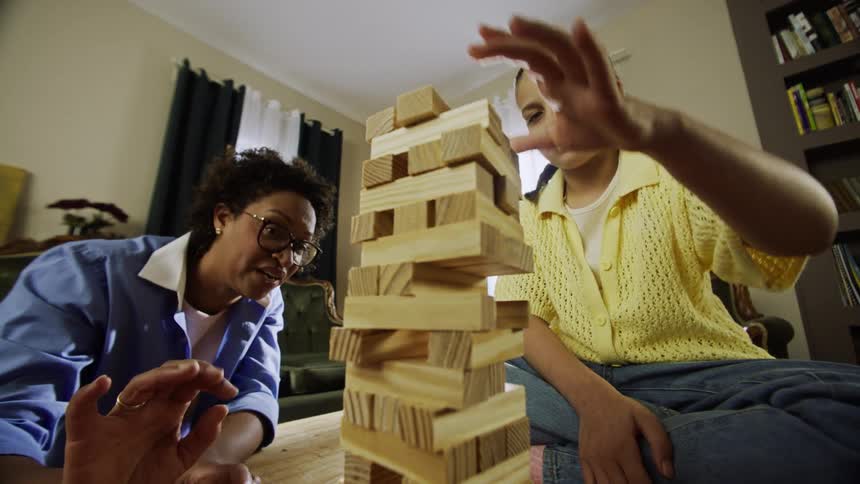 Family plays jenga together in a living room