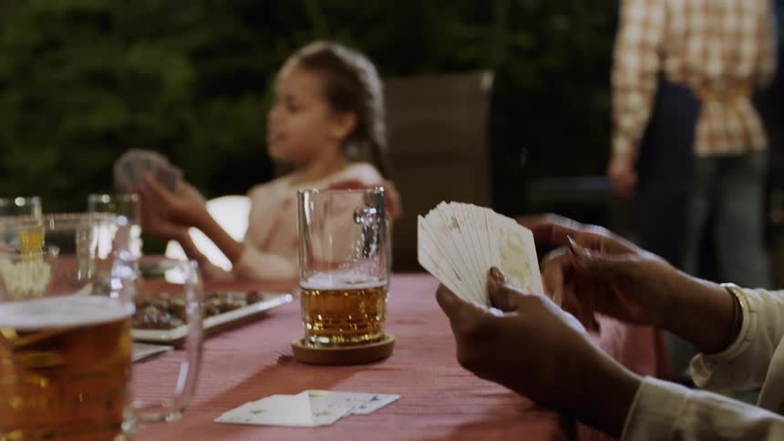 A family plays cards at a table outside