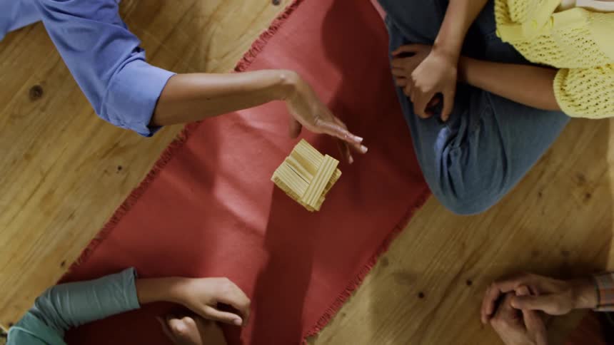A group of four teens sits on the floor playing a game of jenga