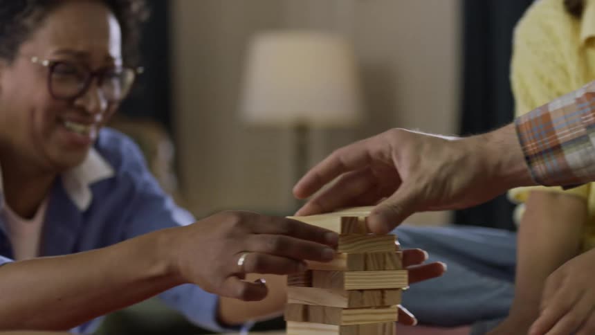 A family sit around a table and play a game with wooden blocks