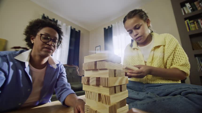 Family gathered around coffee table stacking jenga blocks to start a game