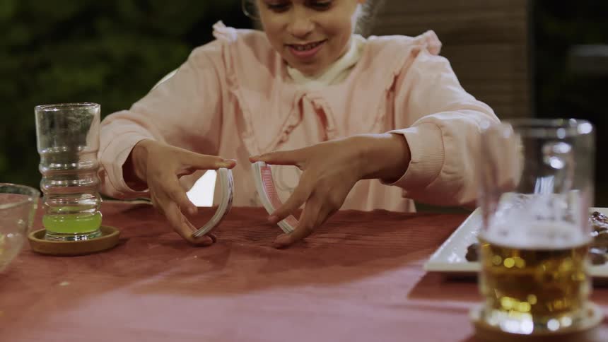 Girl sitting at table playing with deck of cards
