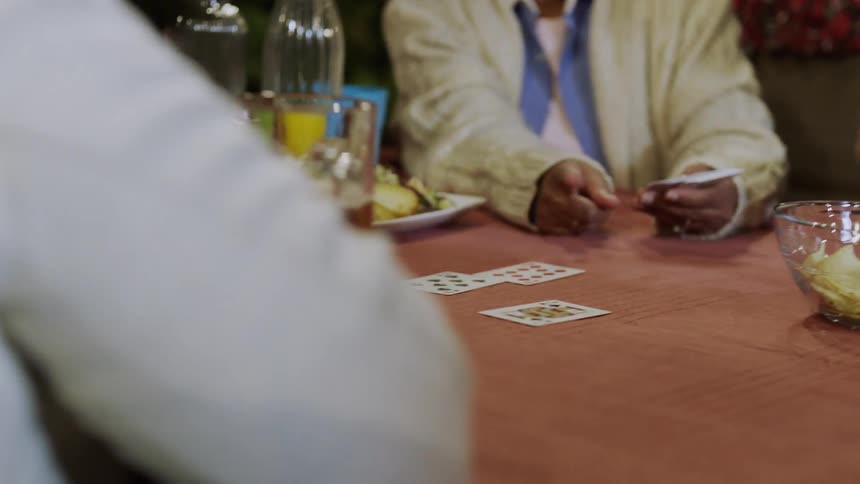 Family play cards together around a table with snacks and drinks