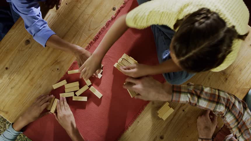 A family sit around a table and play a game with wooden blocks