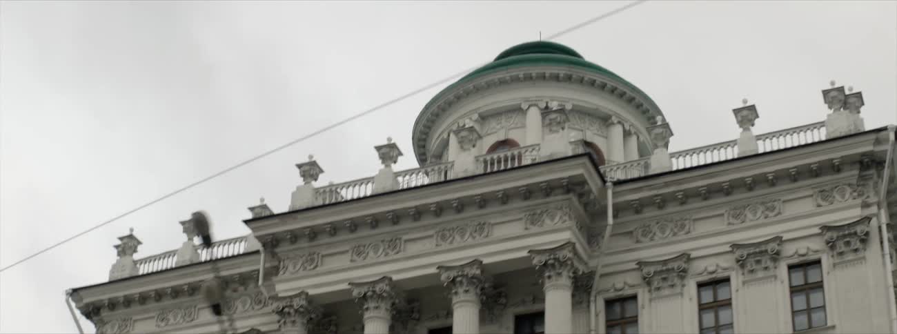 A building with large pillars towers overhead on a cloudy day