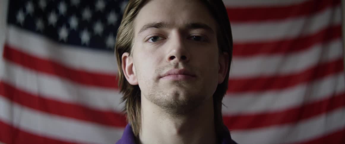 A man stands in front of an american flag