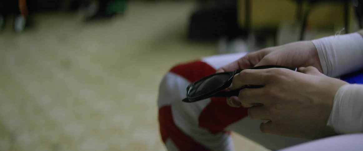 A man is nervously fidgeting with his sunglasses