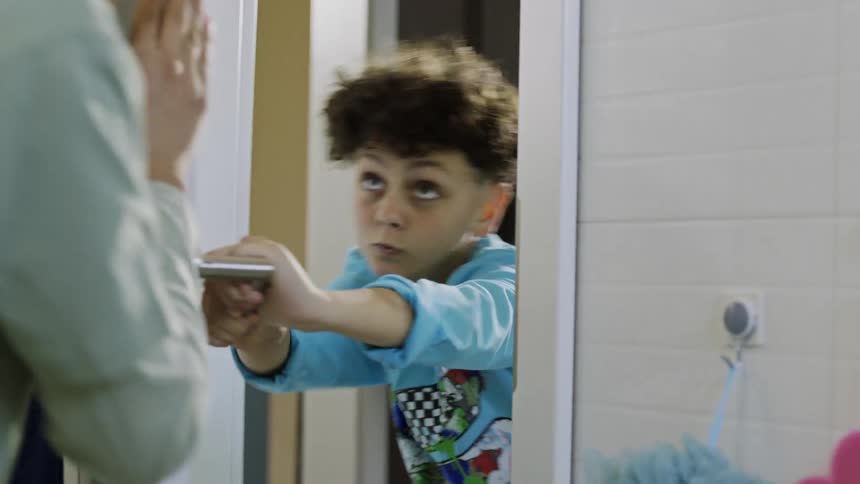 Teenage boy teases his brother by blocking the bathroom door before letting him in