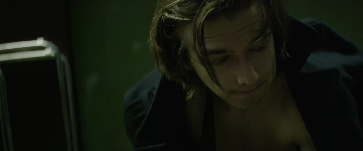 A man leans over in a dark room