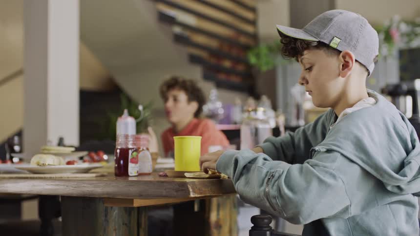 Little boy feeds a treat to his pet dog under the table