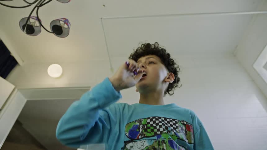 Boy in blue pajamas brushing his teeth then spitting out toothpaste