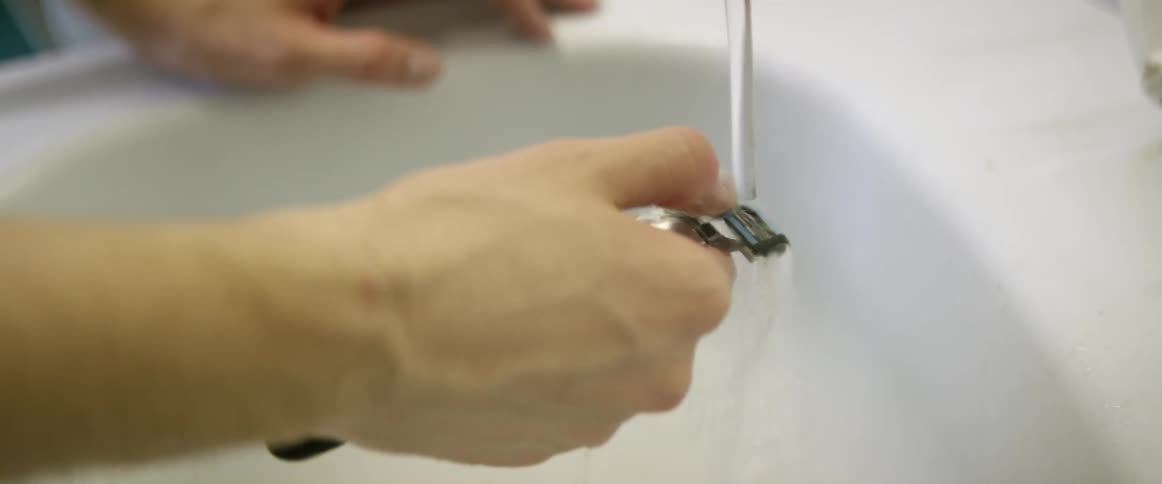 A man rinses his razor off in the sink