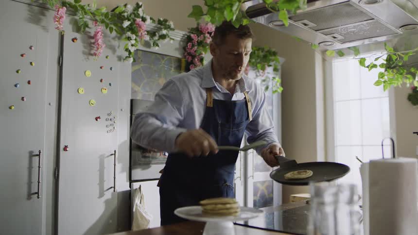 A man finishes cooking pancakes and goes to serve them
