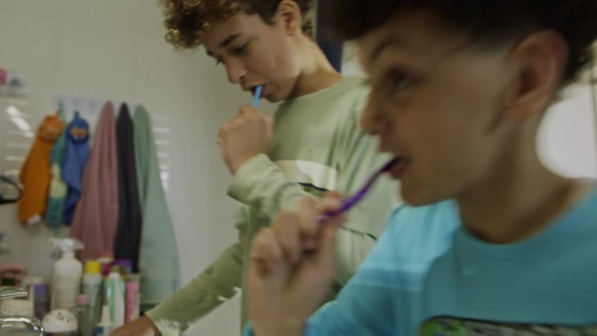 Brothers playfully tease each other while brushing their teeth