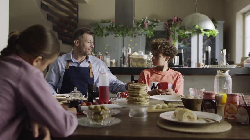 A father and children enjoy a cozy breakfast together at the kitchen table