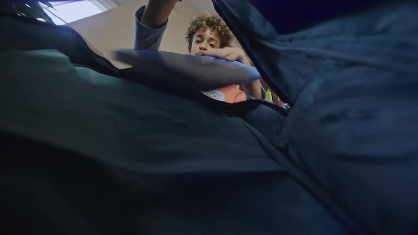 A boy empties a bag reaching in as seen from the perspective inside the bags opening