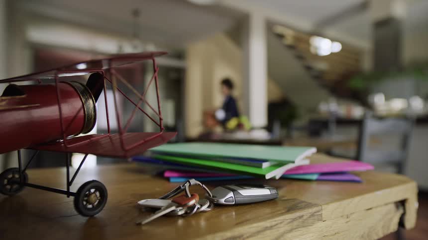 A mother in business attire and her daughter rush through their morning routine with the mother grabbing her keys from a table before they leave the house