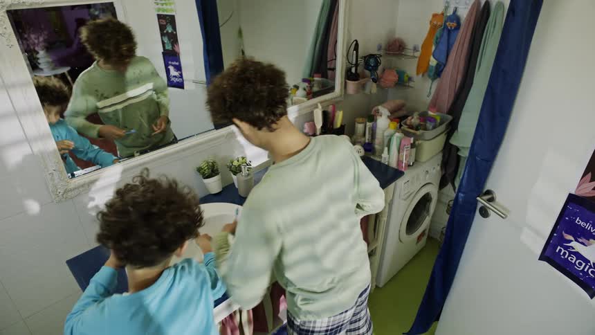 Two brothers playfully fight in the bathroom while brushing their teeth