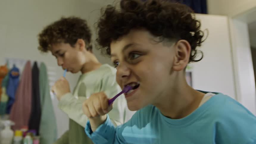Two boys brush their teeth together in the bathroom