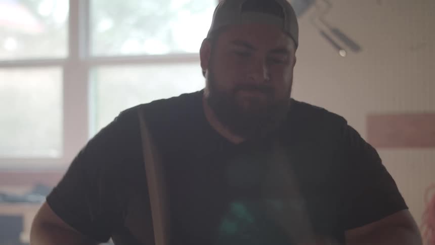 Close up of a male drummer playing a drum set indoors during daytime