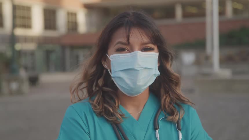 Female health professional wears a stethoscope and a surgical mask outdoors