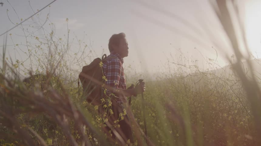 A man stands in a field while wearing hiking gear