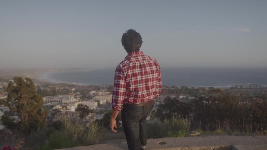 A man is overlooking the town from a hill