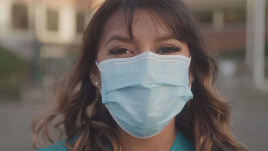 A female healthcare worker wearing a medical mask looking towards camera