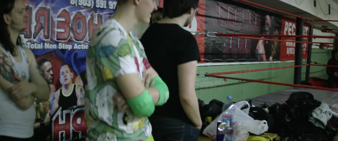 A man walks past other people standing near a fighting ring