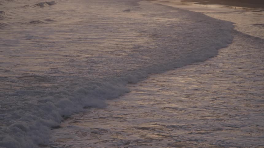 The waves cover the sand on the beach