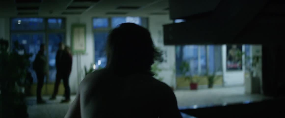 A wrestler hunches over in pain as he walks through a building