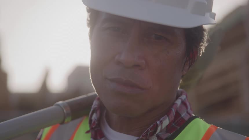 The construction worker stands on the work site on a sunny day