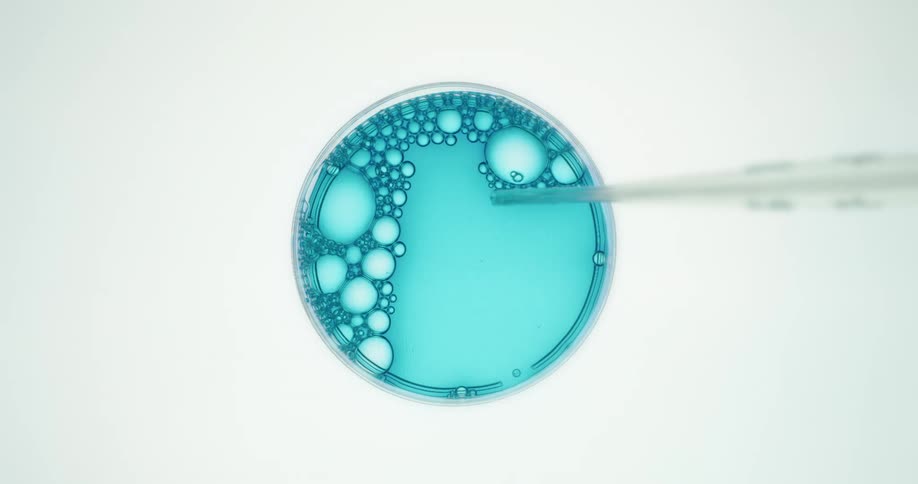 Blue chemical solution being tested with a pipette in a laboratory setting
