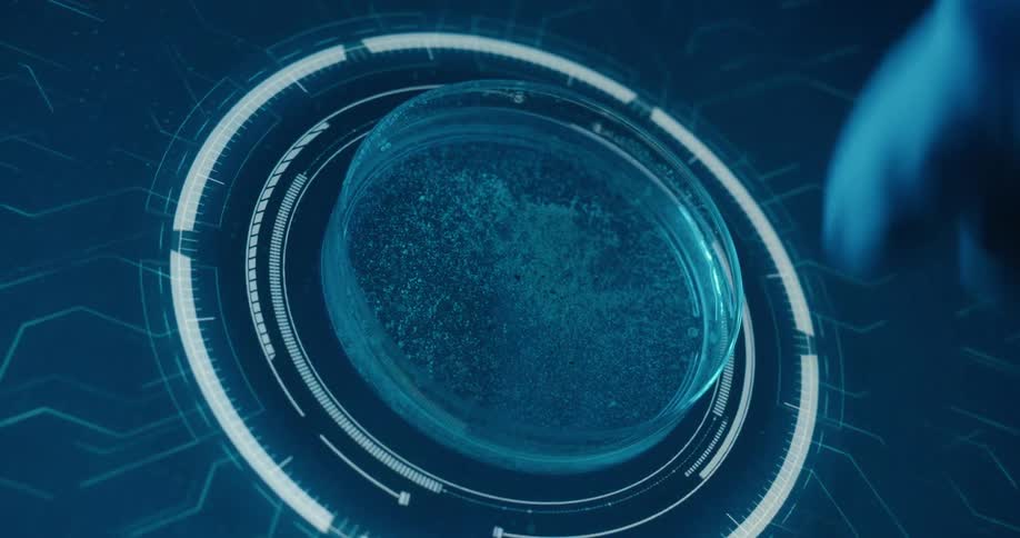 A persons arm wearing medical gloves places a petri dish on a screen that analyzes its contents