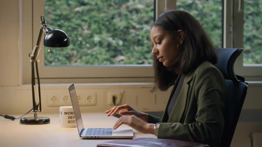 Woman working on a laptop at a desk in a modern office setting
