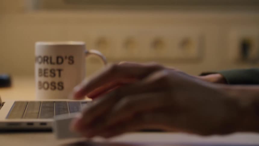 A persons hands picking up a small white box and turning a knob that comes out on top of it then starts typing on the laptop