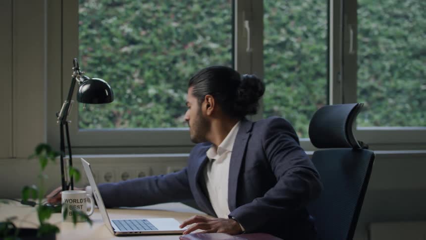 The worker sits at the desk and opens his laptop
