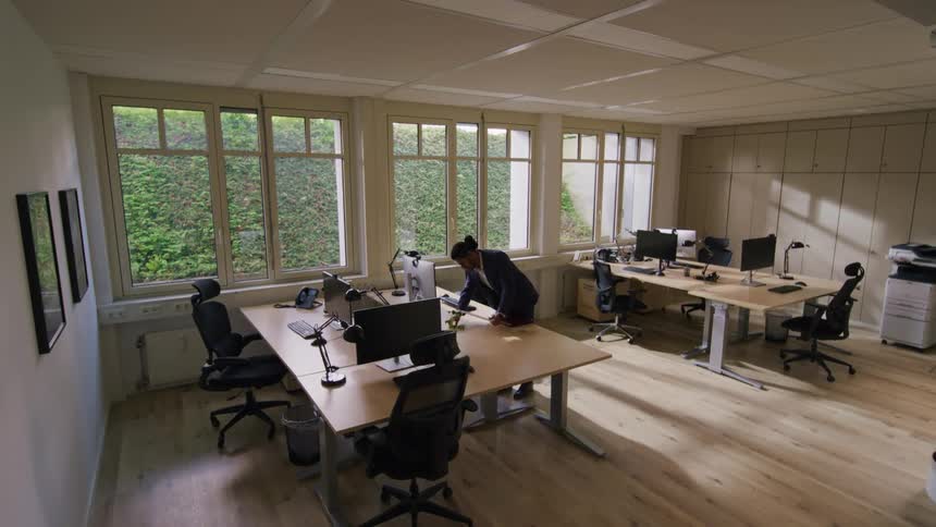 The man walks over and sits at his desk