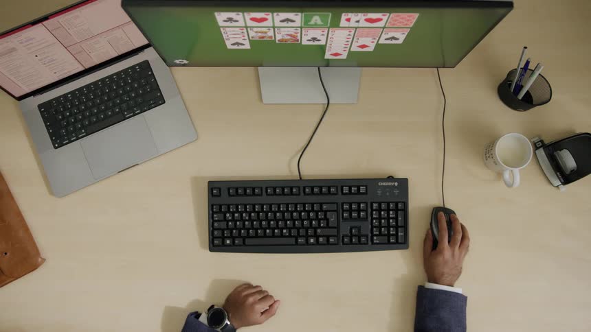 Hands of someone playing card game on a computer with a mouse at daytime