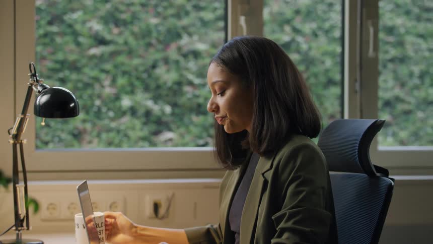 A woman works on a laptop at a desk in a bright modern office