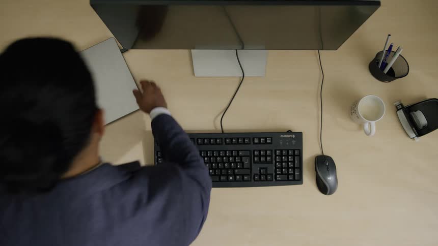 Man arriving at his office sets up his laptop and activates his desktop computer